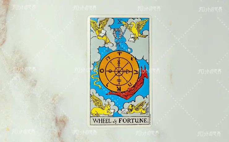 ウェイト＝スミスタロットの運命の輪のカード。中央に大きな輪と象徴的なシンボルが描かれ、周囲には四大元素を象徴する存在が配置されている。青空と雲を背景にしたタロットカードの一枚。